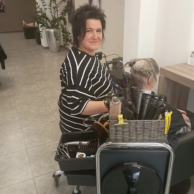 Eine Frau sitzt in einem Friseursalon, während ihr die Haare frisiert werden.