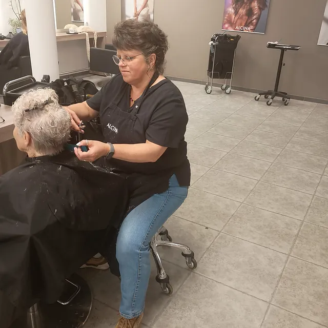 Eine Friseurin schneidet einer Kundin die Haare in einem modernen Friseursalon. 