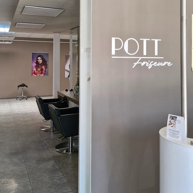 Friseursalon mit dem Schriftzug "Pott Friseure" auf einem auffälligen Schild, das die Kunden willkommen heißt. 