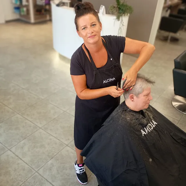 Eine Frau erhält einen Haarschnitt von einer Friseurin in einem stilvollen Salon.