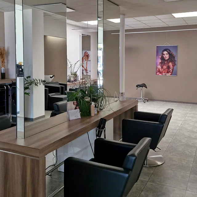 Innenansicht eines Friseursalons mit mehreren Stühlen und Spiegeln für Kunden.